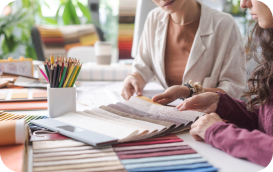 Two people discuss colorful fabric samples at a desk.